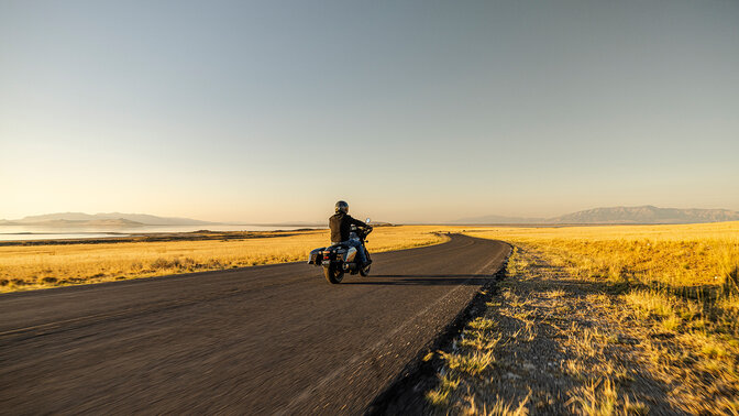 Personnage sur une Honda CMX1100 Rebel vue de derrière sur route.